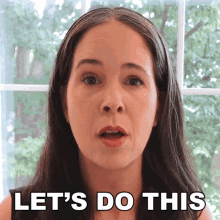 a woman says " let 's do this " while standing in front of a window