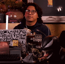 a man sitting at a desk with a book that says caballo de troya