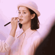 a woman wearing a pink hat is applying makeup to her face