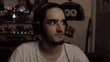 a man wearing headphones looks at the camera in front of a wall with a penguin on it