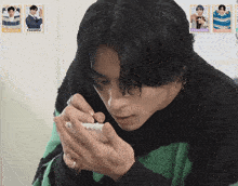 a man in a green and black sweater is writing on a notebook