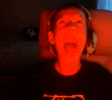 a person wearing headphones and a black shirt with the word t on it is screaming