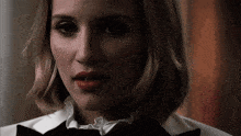 a close up of a woman wearing a tuxedo and ruffled collar