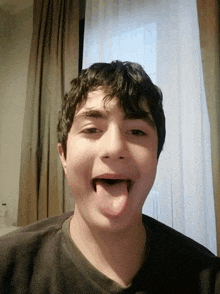 a young boy sticking his tongue out while wearing a black shirt