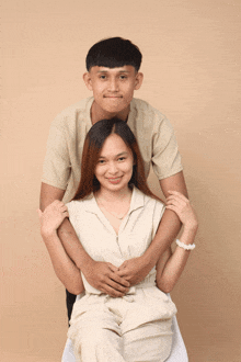 a man and woman posing for a picture with the woman sitting on a chair