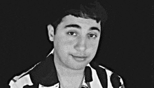 a black and white photo of a young man wearing a black and white shirt