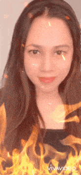 a woman 's face is surrounded by flames and the word vivavideo is on the bottom