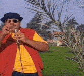 a man wearing sunglasses and a hat is singing into a microphone .