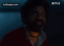 a man with a beard is looking at the camera in a dark room with a netflix logo in the corner .