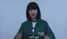 a girl wearing a green jacket with the number 12 on it is waving her hands and saying let 's go .