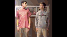 two young men are standing next to each other in front of a picture .