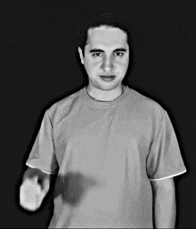 a man in a grey t-shirt is pointing at the camera