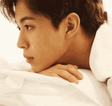 a close up of a young man laying on a bed with his head resting on his hand .