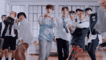 a group of young men are dancing in a room and one of them is wearing a sweater with the letter e on it
