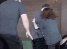 a group of people are hugging each other in a room . one of the people is wearing a hoodie .