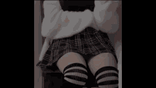 a woman in a plaid skirt is taking a selfie with her phone