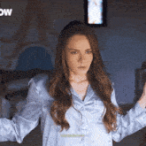 a woman in a blue shirt is standing in front of a sign that says " now "
