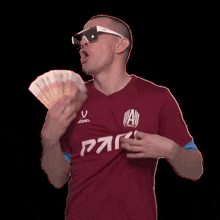 a man wearing sunglasses and a shirt that says par holds a bunch of money