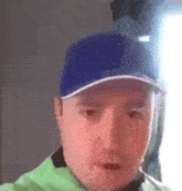a man is wearing a blue hat and a green jacket .