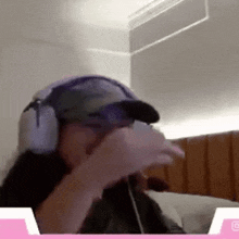 a woman wearing headphones and a baseball cap is sitting on a bed .