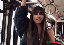 a woman with long hair and bangs is riding a bus