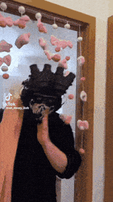 a man wearing a mask is standing in front of a door with a string of pink stuffed animals hanging from it