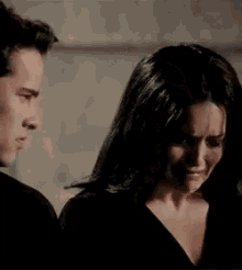 a man and a woman are standing next to each other . the woman is crying while the man looks on .