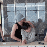 a man wearing a beanie that says ' i love you ' on it kisses another man