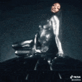 a woman in a silver bodysuit is laying on her stomach .