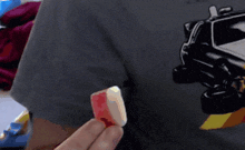 a person holding a piece of candy in front of a back to the future car