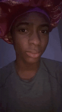a young man wearing a pink and purple hat