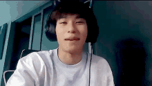 a young man wearing headphones and a cat ear headset is making a funny face .