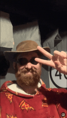 a man with a beard wearing a hat and sunglasses giving the peace sign