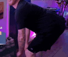 a man in a black shirt and black shorts is squatting in front of a record player