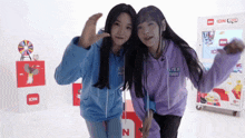 two girls are posing for a picture and one has a hoodie that says even pink
