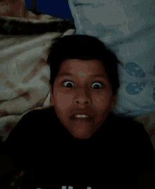 a young boy laying on a bed making a face