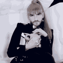 a man with a ponytail and a beard is sitting on a white couch made with the reface app