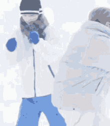 a group of people are standing in the snow . one of the people is wearing a hat and scarf .