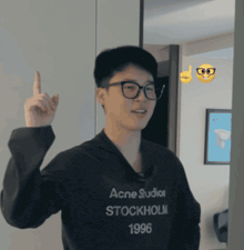 a man wearing a black acne studios stockholm 1996 sweatshirt points up