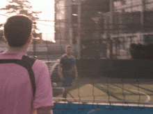 a man in a pink shirt stands in front of a net