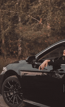 a man is driving a black car with the word monster in the background