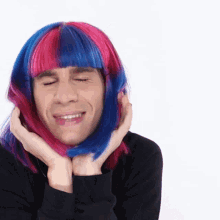 a man wearing a pink and blue wig is smiling