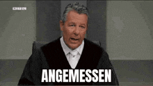 a man in a judge 's robe is sitting in front of a microphone and saying angemessen .