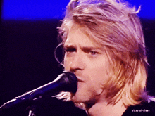 a close up of a man singing into a microphone with the words signs-of-sleep above him