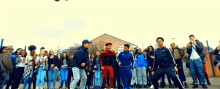 a group of young people are dancing in front of a building that says ' a ' on it