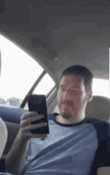 a man sitting in a car looking at a cell phone