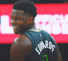 a basketball player named edwards is smiling and looking over his shoulder
