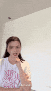 a woman wearing a white t-shirt that says " hooduseries " on it