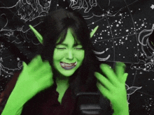 a woman wearing green gloves and elf ears is smiling