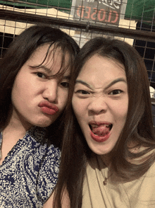 two girls are making funny faces in front of a closed sign